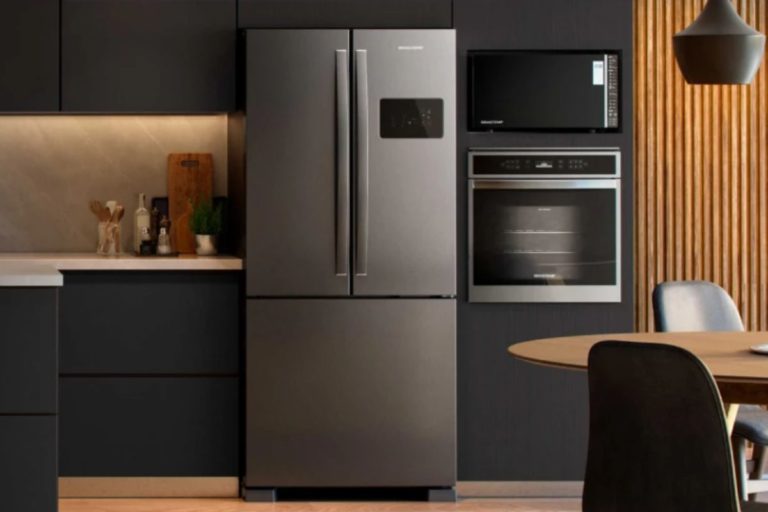 Cozinha com móveis planejados incluindo geladeira, micro-ondas e forno elétrico