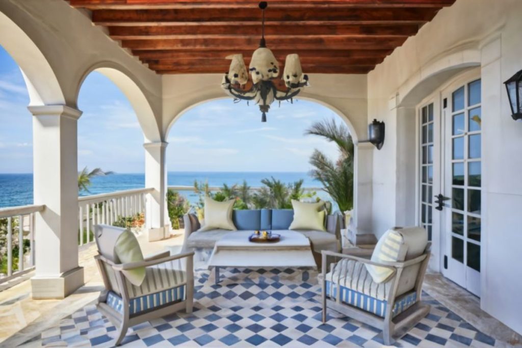 Varanda estilo mediterrâneo com móveis claros e detalhes em tons de azul.