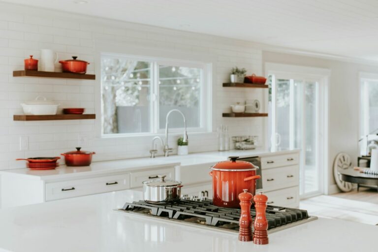Cozinha planejada branca com louças vermelhas.