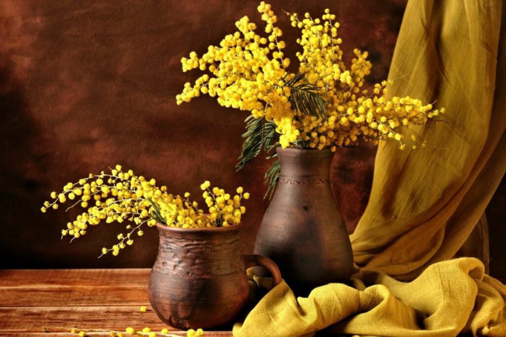 Vaso de cerâmica rústico com arranjo de flores amarelo.